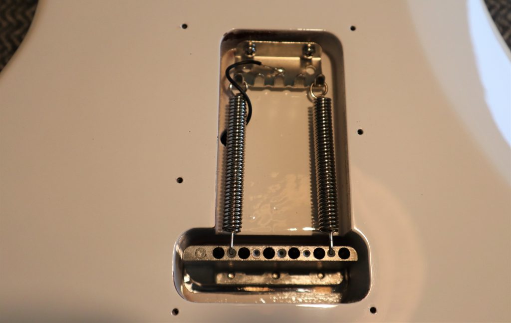 reveals what's going on under the backplate of a guitar that has a synchronized tremolo bridge